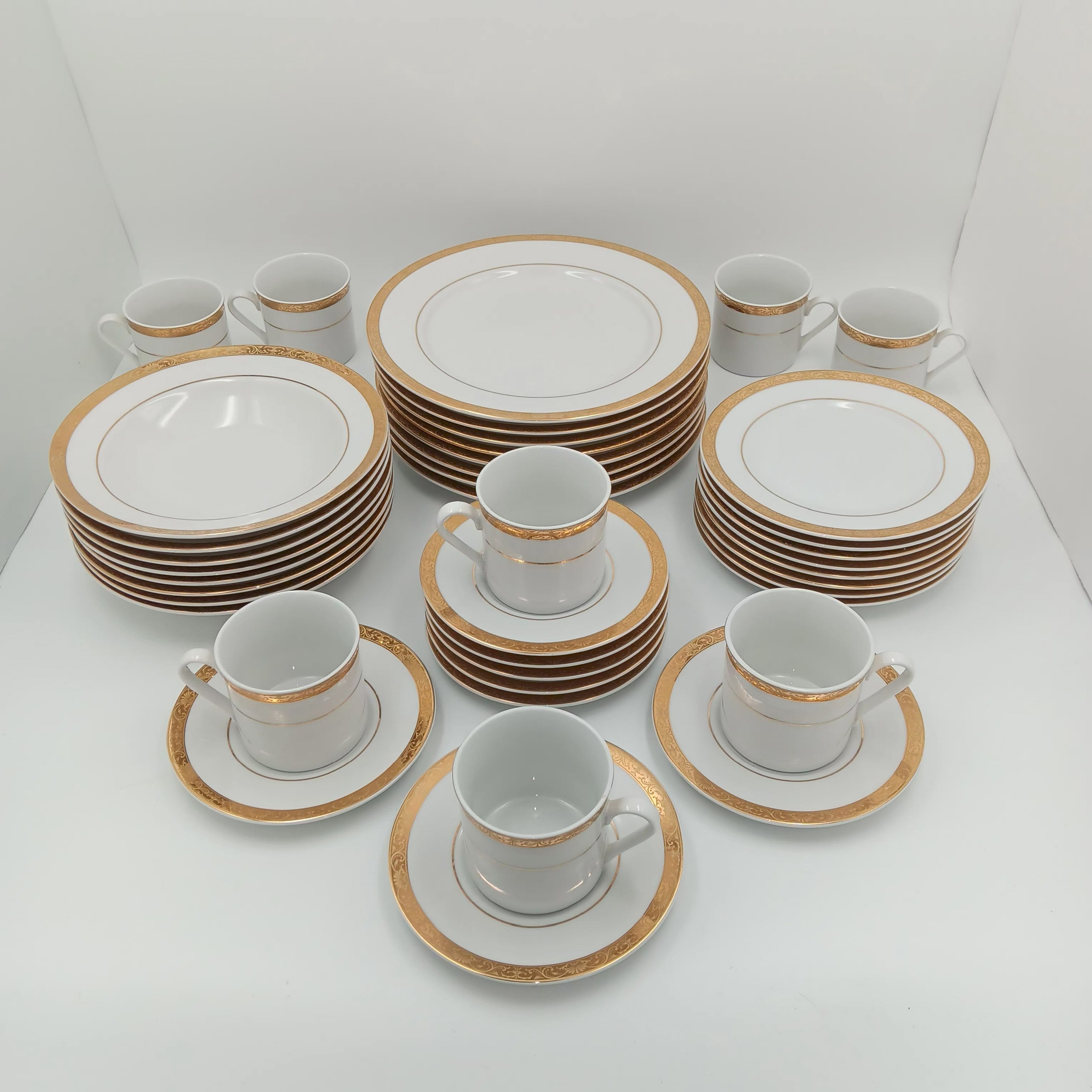 30-piece fine china dinnerware set with white porcelain and gold rim, arranged on white surface