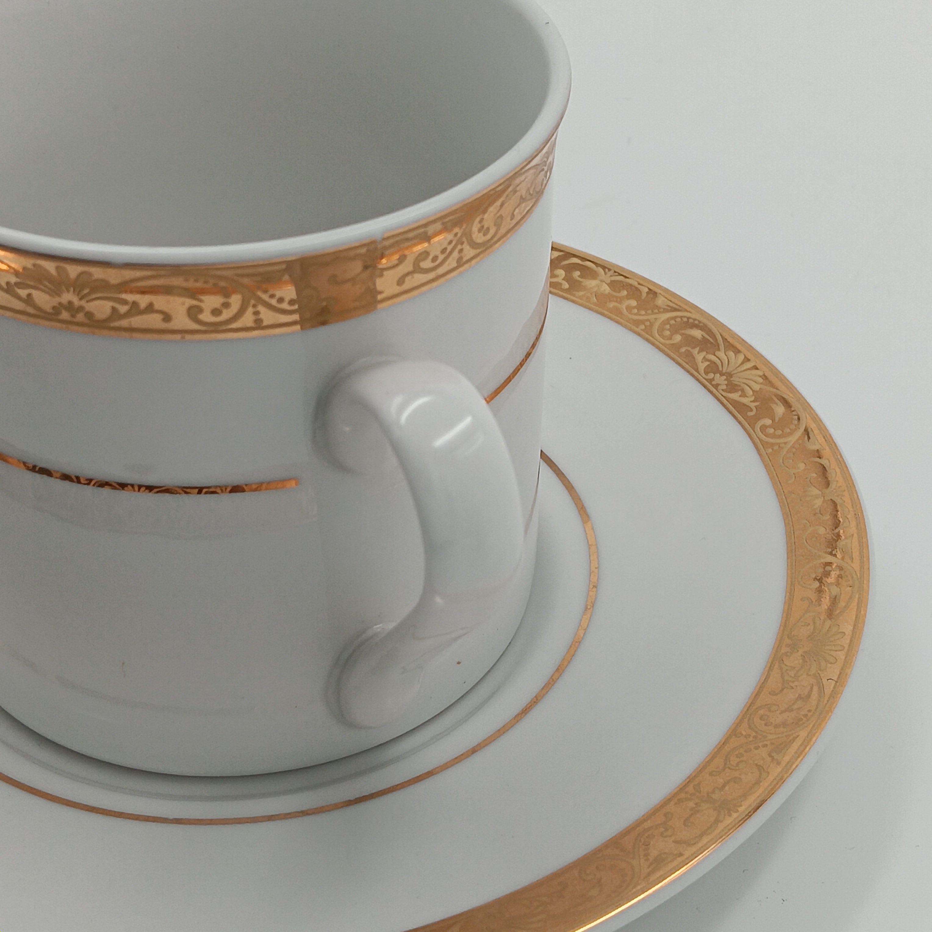 White porcelain teacup and saucer with gold detailing, part of 30-piece china set