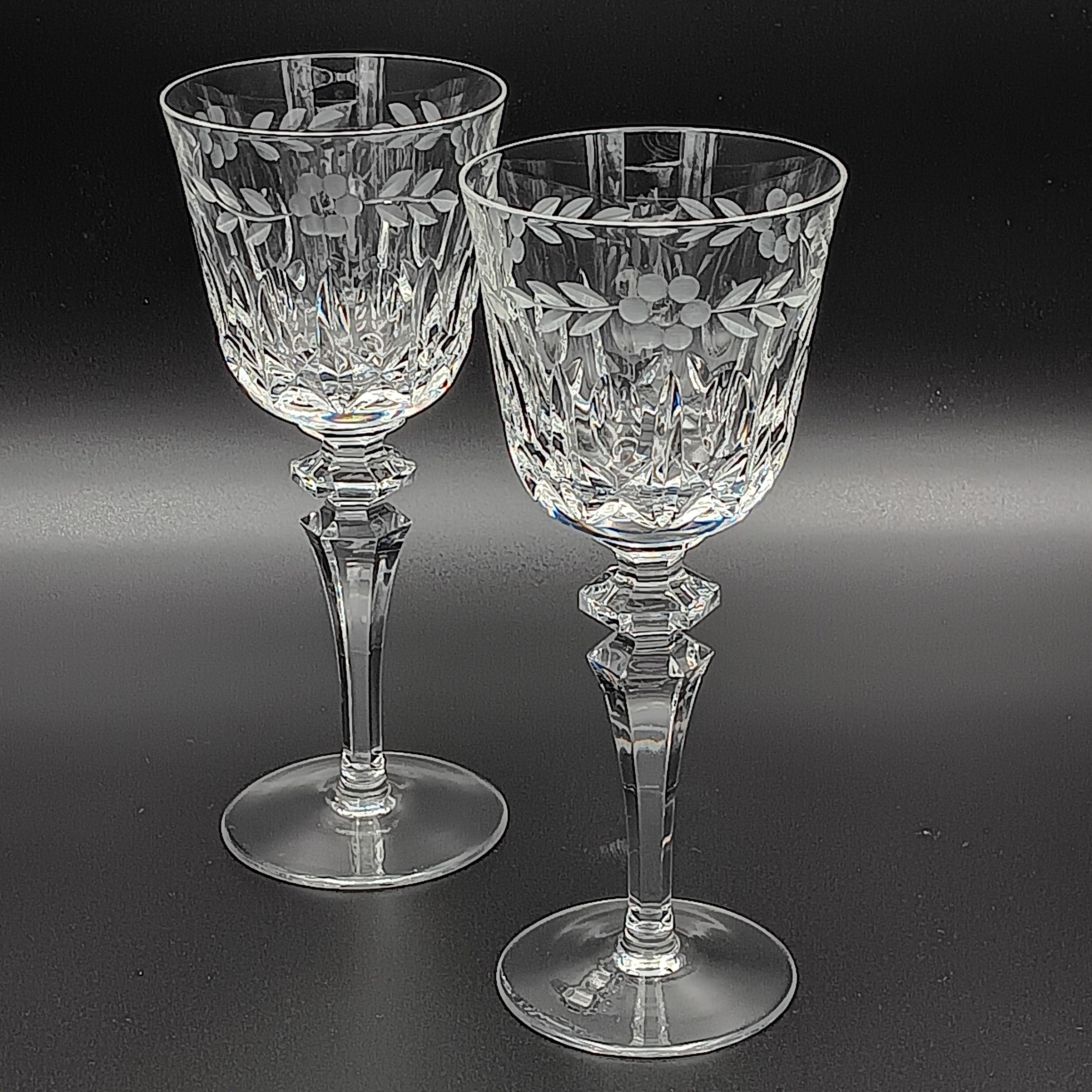 Two crystal glasses with floral etching on a black background