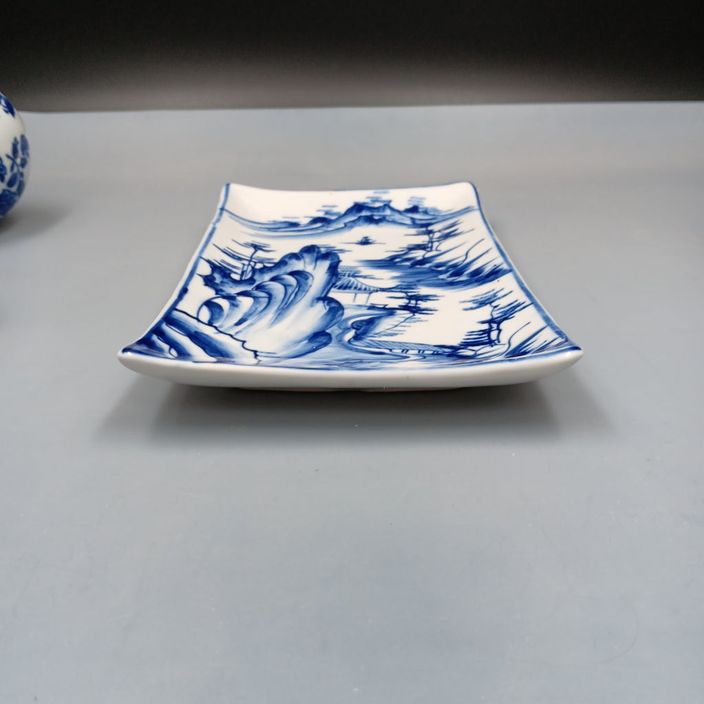 Antique Chinese blue and white porcelain dish with hand-painted landscape scene featuring mountains, trees, and a pavilion in cobalt blue on a rectangular ceramic dish.