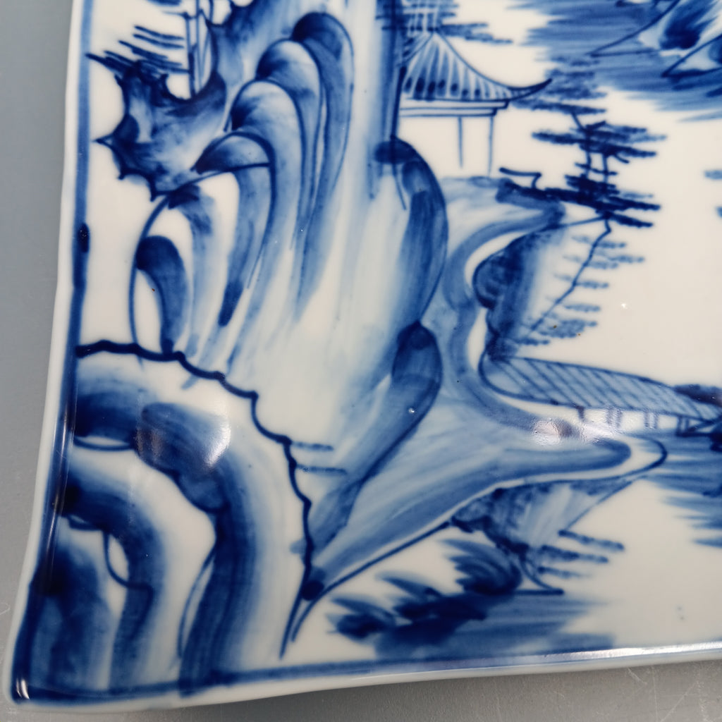 Antique Chinese blue and white porcelain plate with hand-painted landscape scene featuring mountains, trees, and a pavilion in cobalt blue on a rectangular ceramic dish.