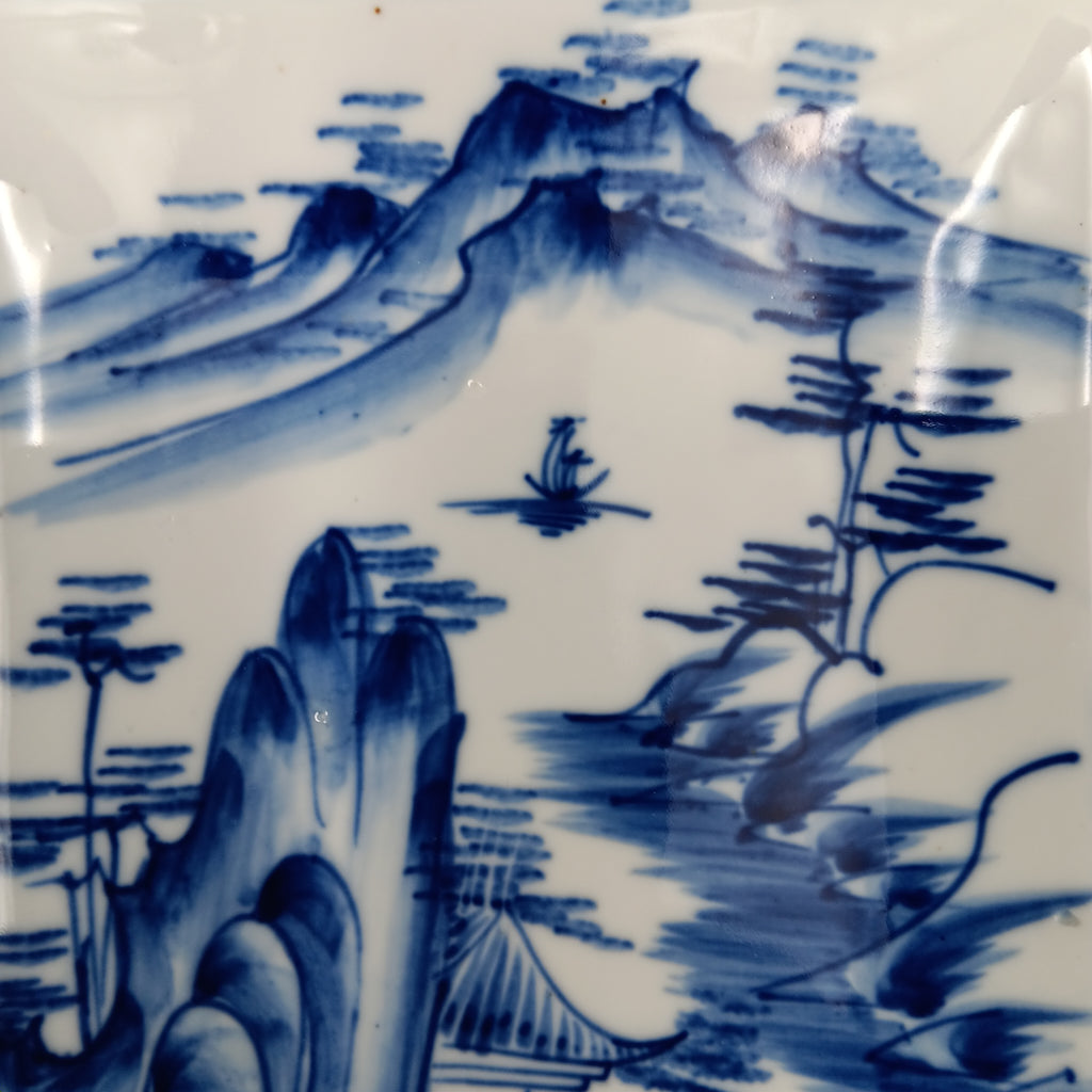 Antique Chinese blue and white porcelain dish with hand-painted landscape scene featuring mountains, trees, and a pavilion in cobalt blue on a rectangular ceramic dish.