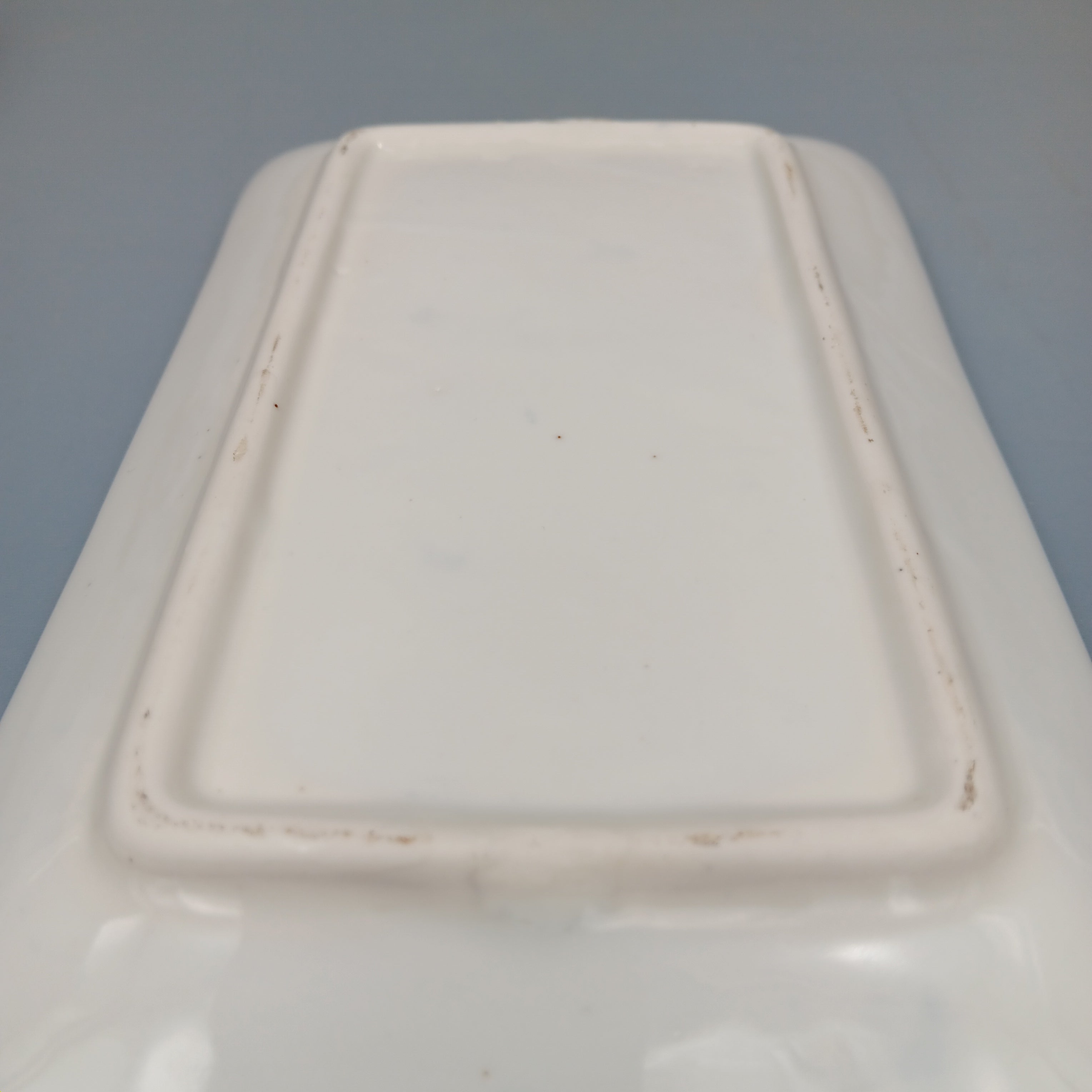 Underside of a rectangular white porcelain plate showing raised foot rim and subtle kiln marks, indicative of late Qing to early Republic period craftsmanship.