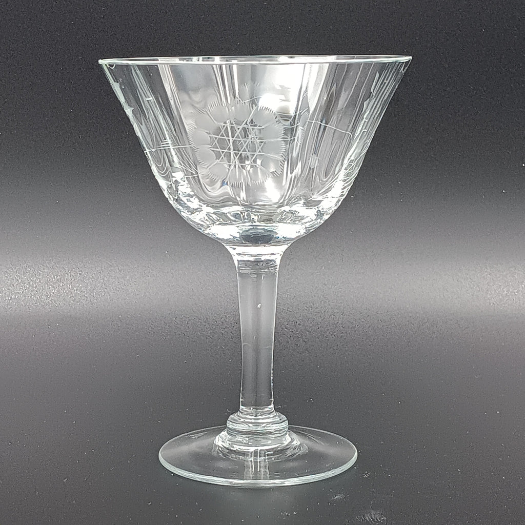 Vintage W J Hughes Cornflower champagne glass with etched floral and geometric patterns, lying horizontally on a dark surface with light highlighting its clear crystal design