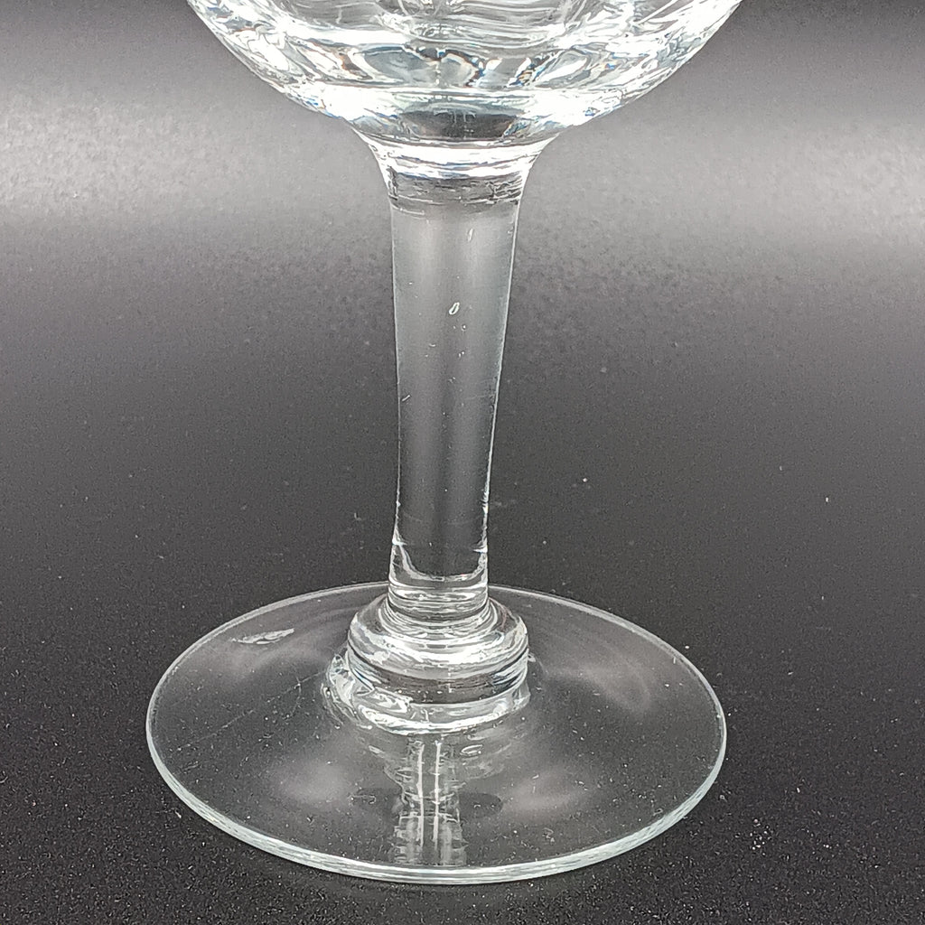 Vintage W J Hughes Cornflower champagne glass with etched floral and geometric patterns, lying horizontally on a dark surface with light highlighting its clear crystal design