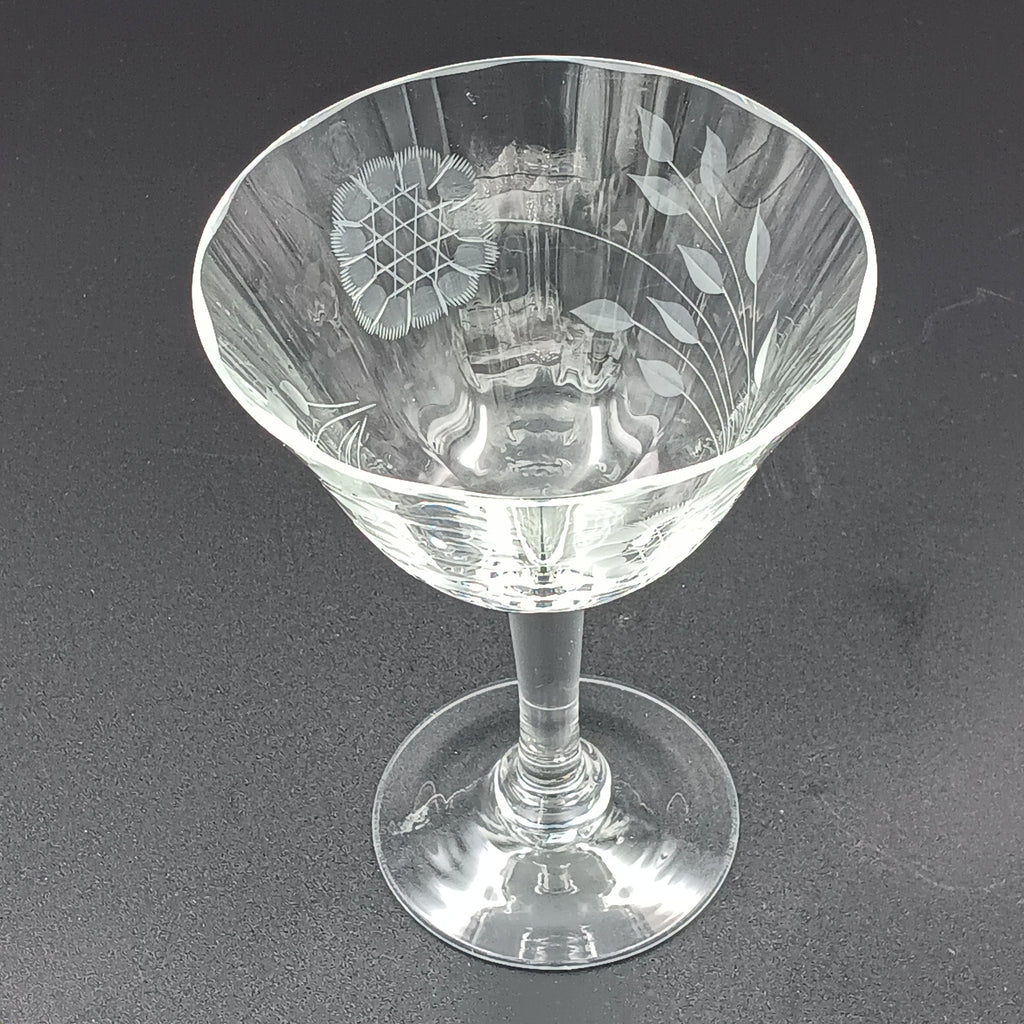 Vintage W J Hughes Cornflower champagne glass with etched floral and geometric patterns, lying horizontally on a dark surface with light highlighting its clear crystal design