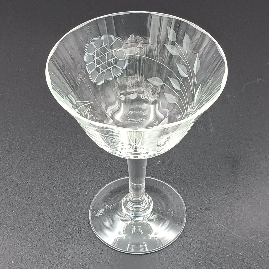 Vintage W J Hughes Cornflower champagne glass with etched floral and geometric patterns, lying horizontally on a dark surface with light highlighting its clear crystal design