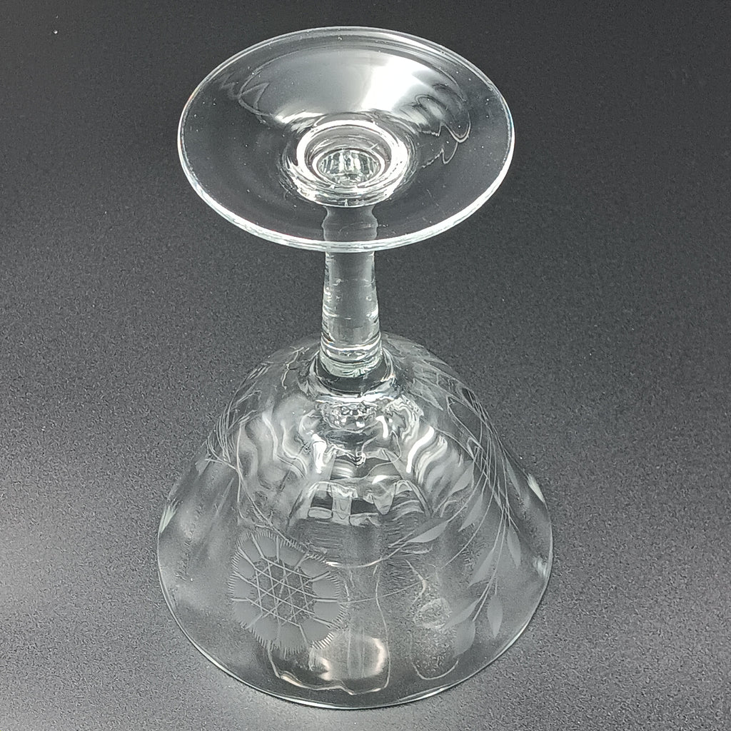 Vintage W J Hughes Cornflower champagne glass with etched floral and geometric patterns, lying horizontally on a dark surface with light highlighting its clear crystal design