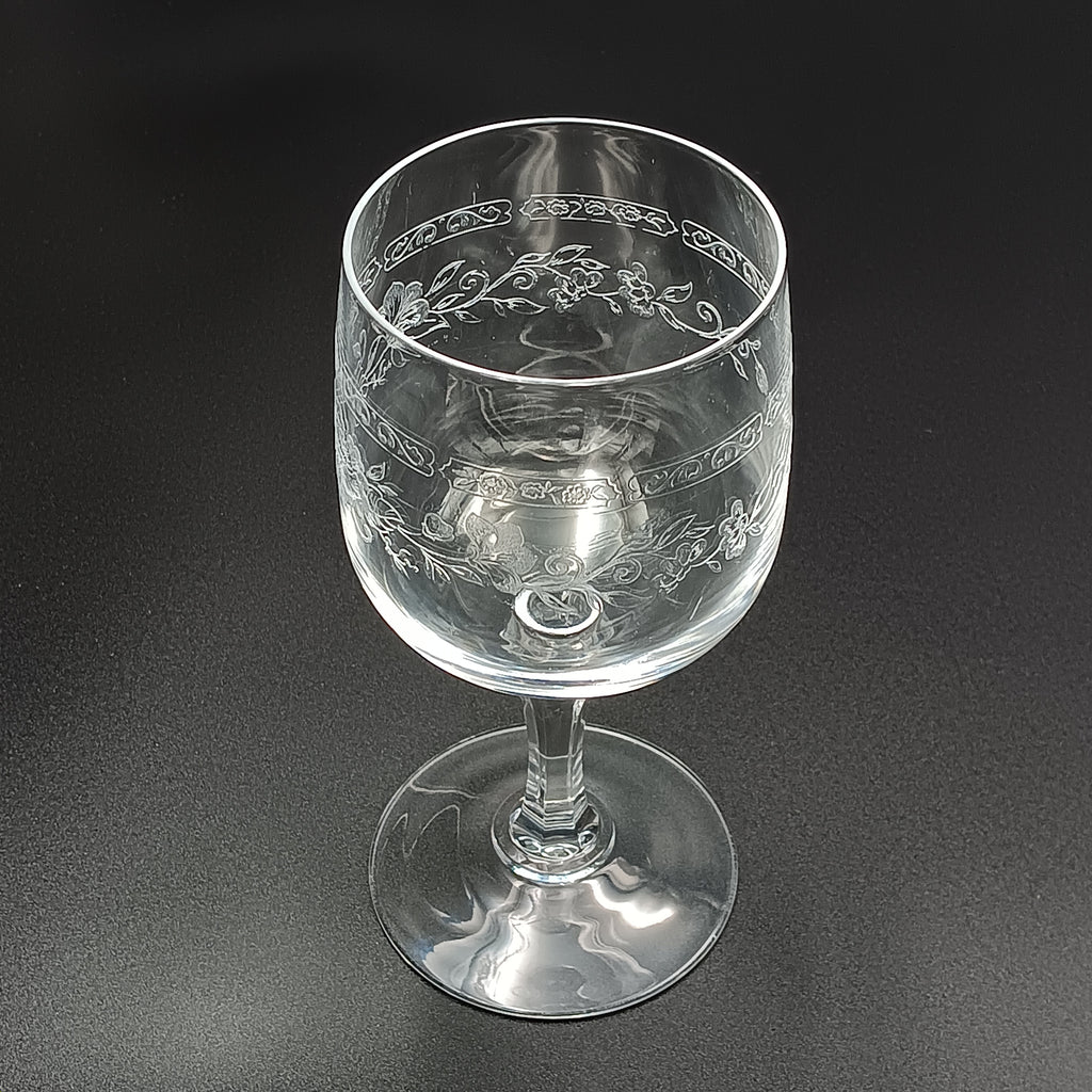 Clear crystal wine glass with etched floral and vine patterns.