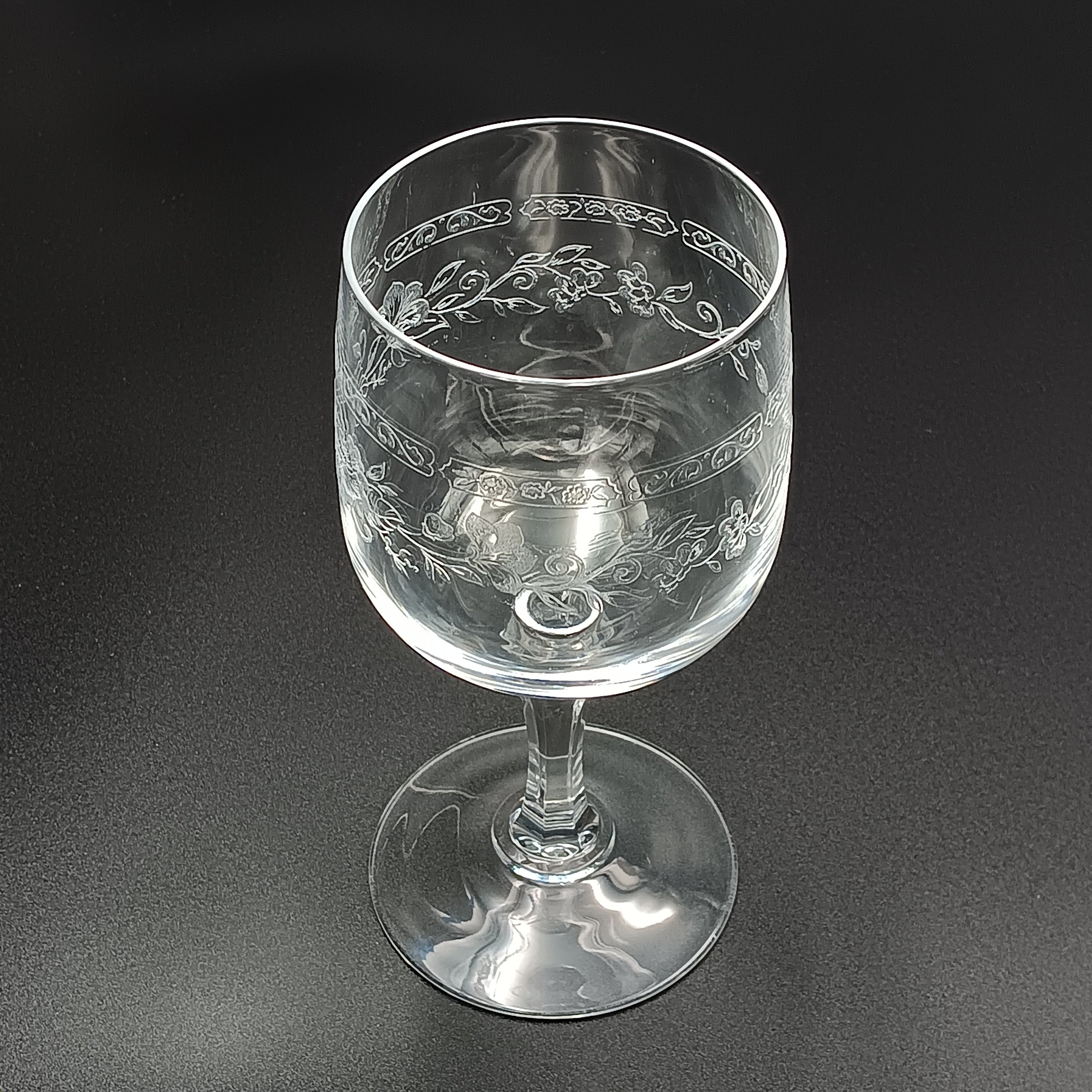 Clear crystal wine glass with etched floral and vine patterns.