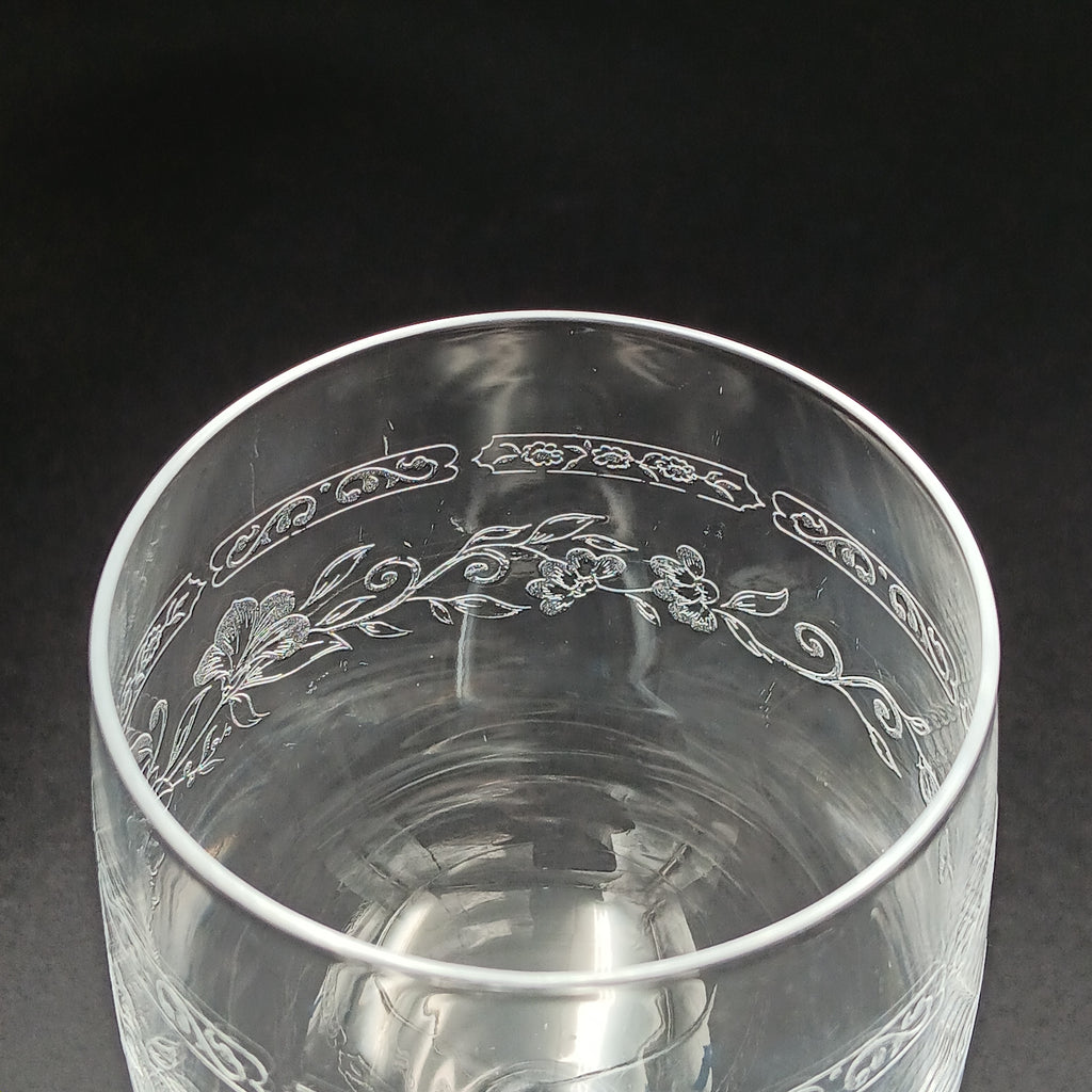 Clear crystal wine glass with etched floral and vine patterns.