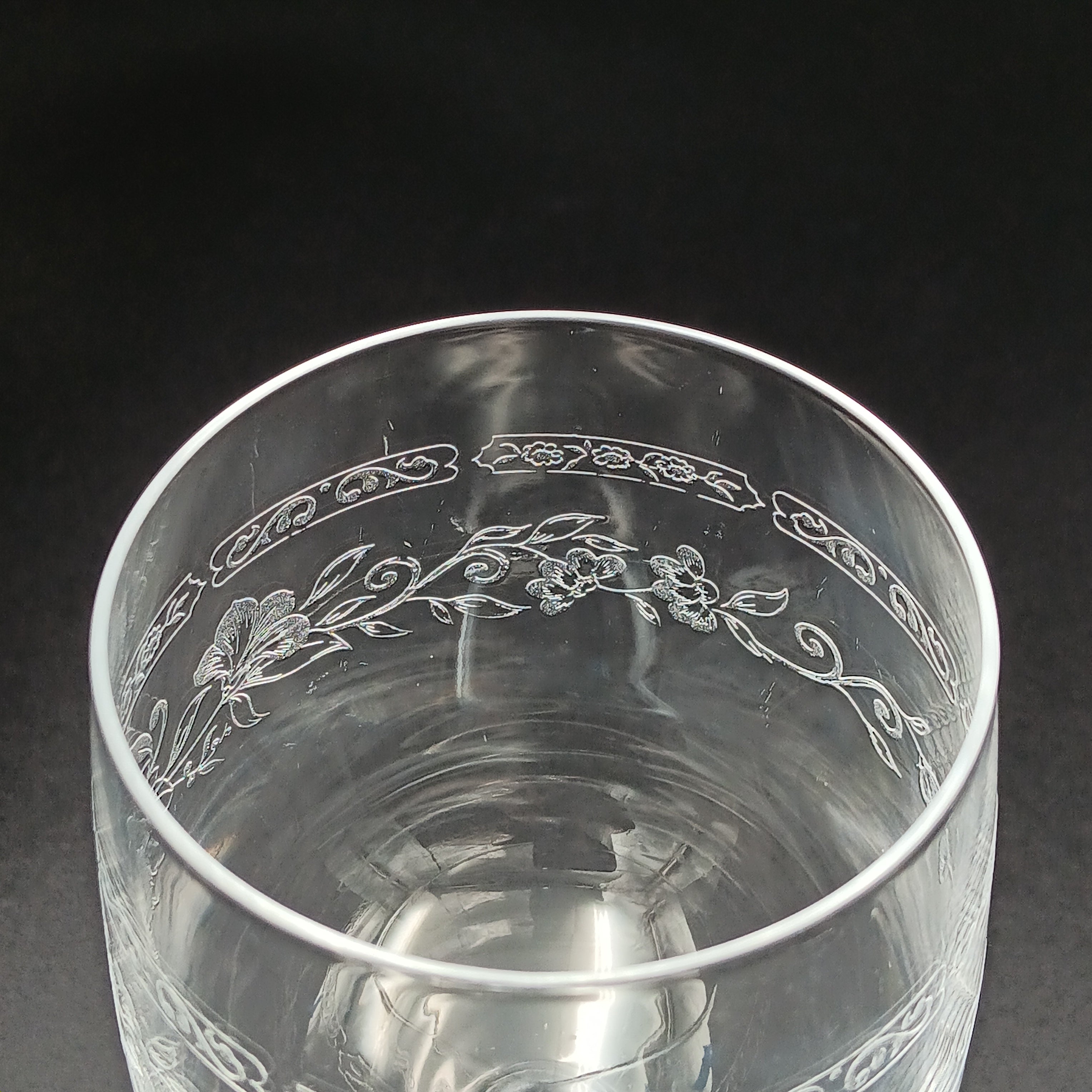 Clear crystal wine glass with etched floral and vine patterns.