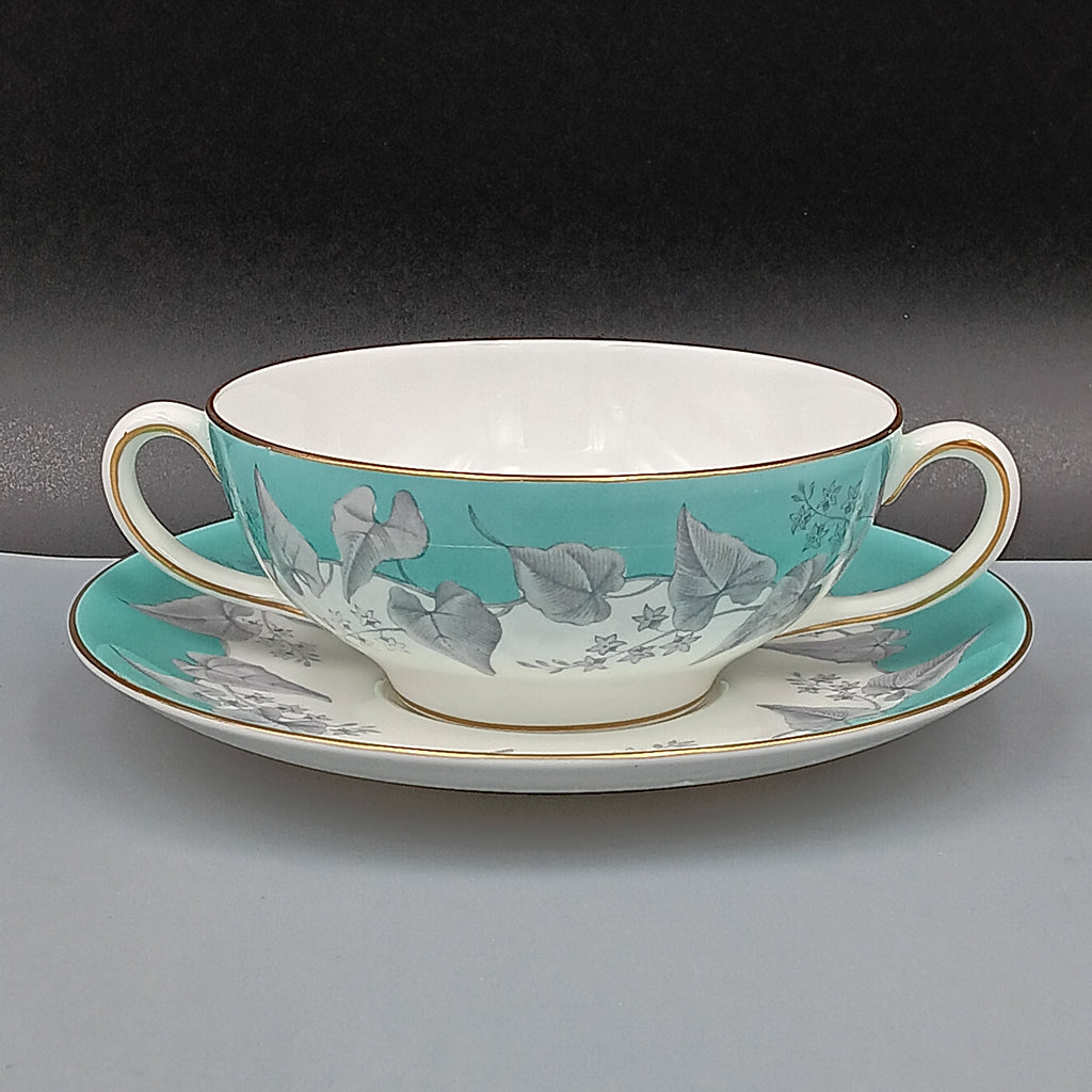Wedgwood 'Buxton' double-handled soup bowl and saucer set featuring a turquoise background with gray and white floral design, accented by gold trim on edges; elegant English porcelain tableware ideal for collectors.