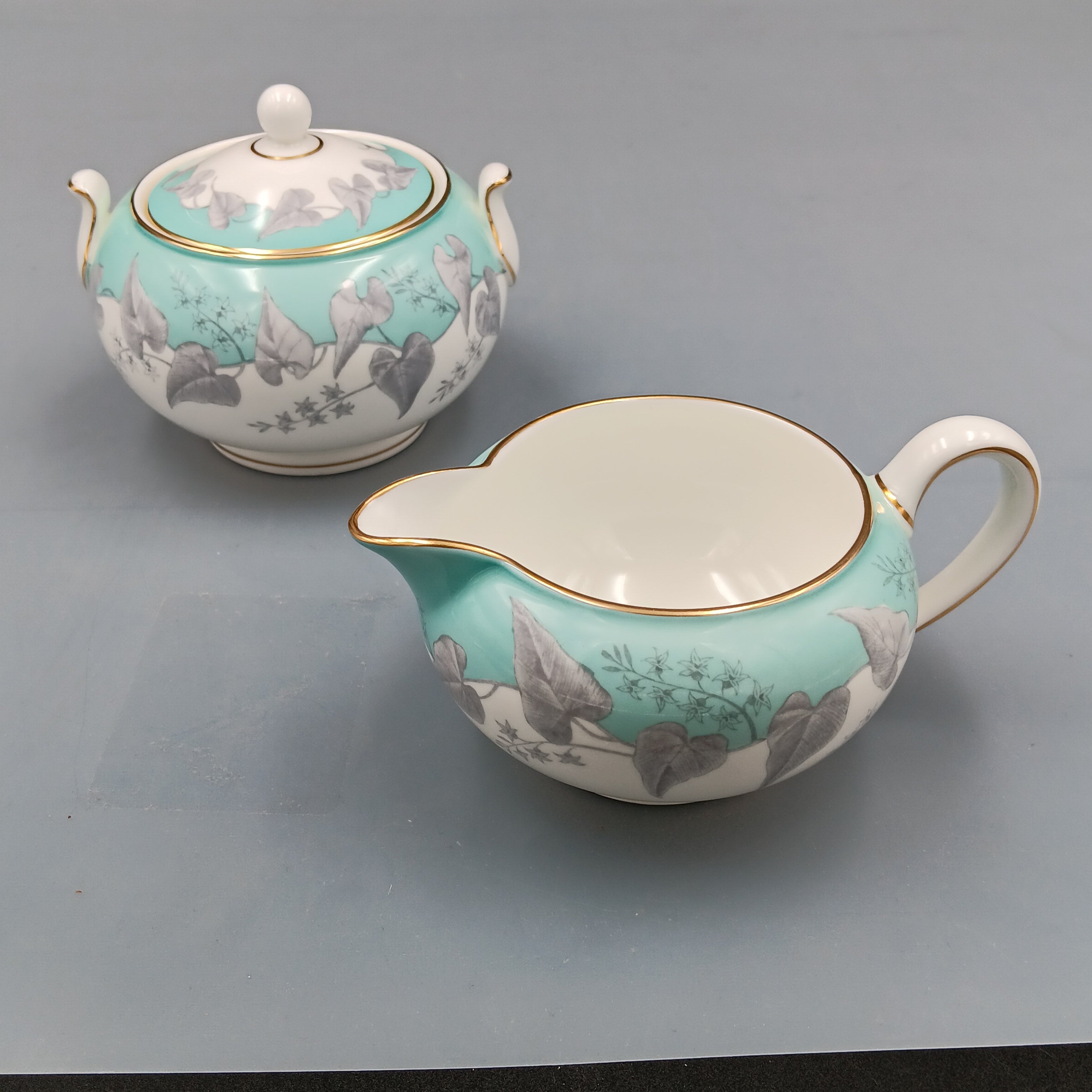 Wedgwood Buxton Turquoise cream and sugar set with gold trim and floral design.