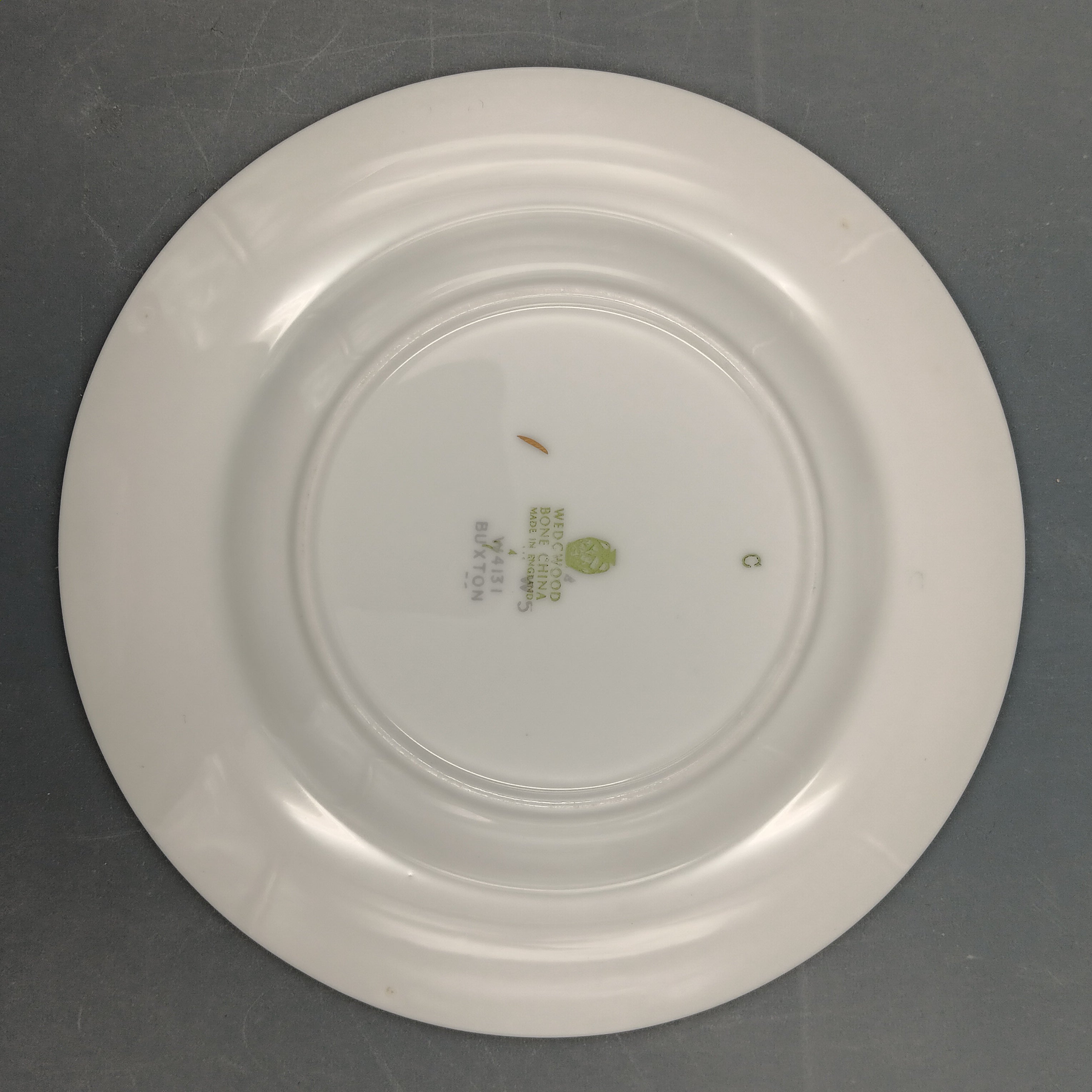 White ceramic plate with a visible brand logo on a gray background