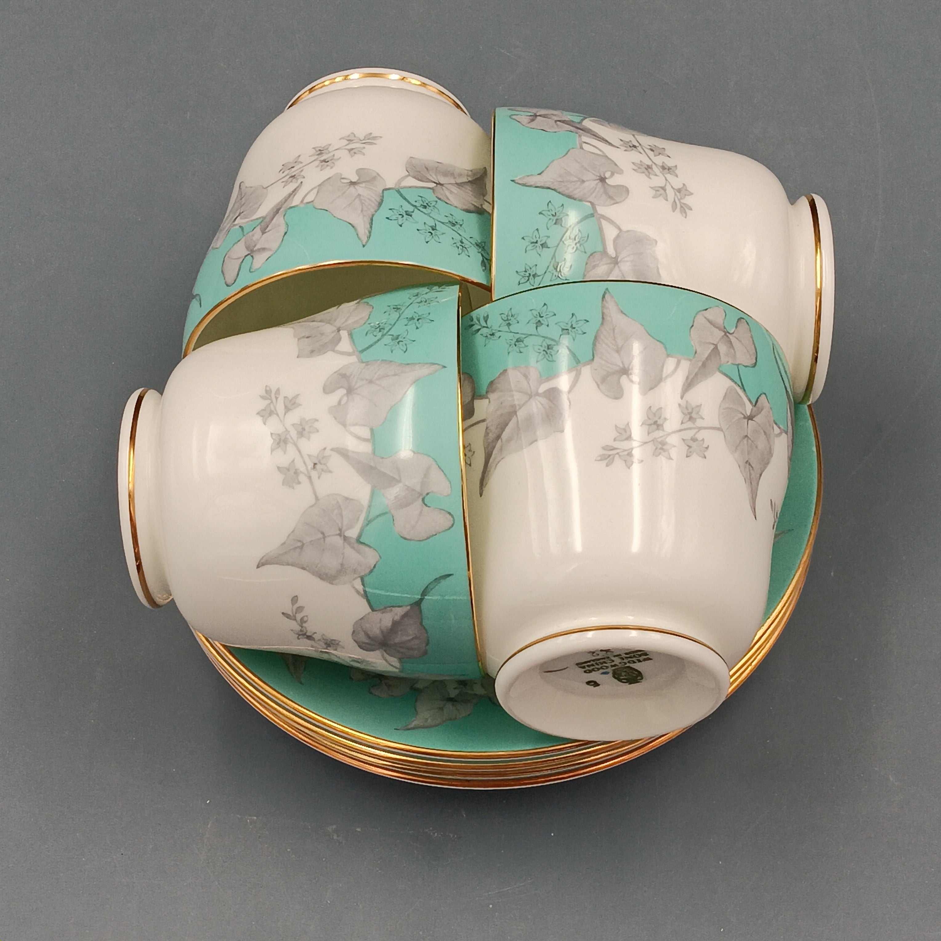 Set of four vintage Wedgwood Buxton Turquoise teacups and saucers with turquoise border, gray floral design, and gold trim