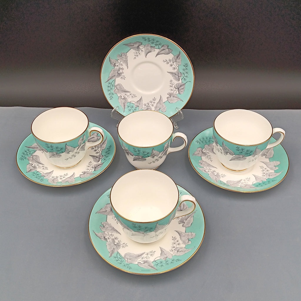 Set of four vintage Wedgwood Buxton Turquoise teacups and saucers with turquoise border, gray floral design, and gold trim