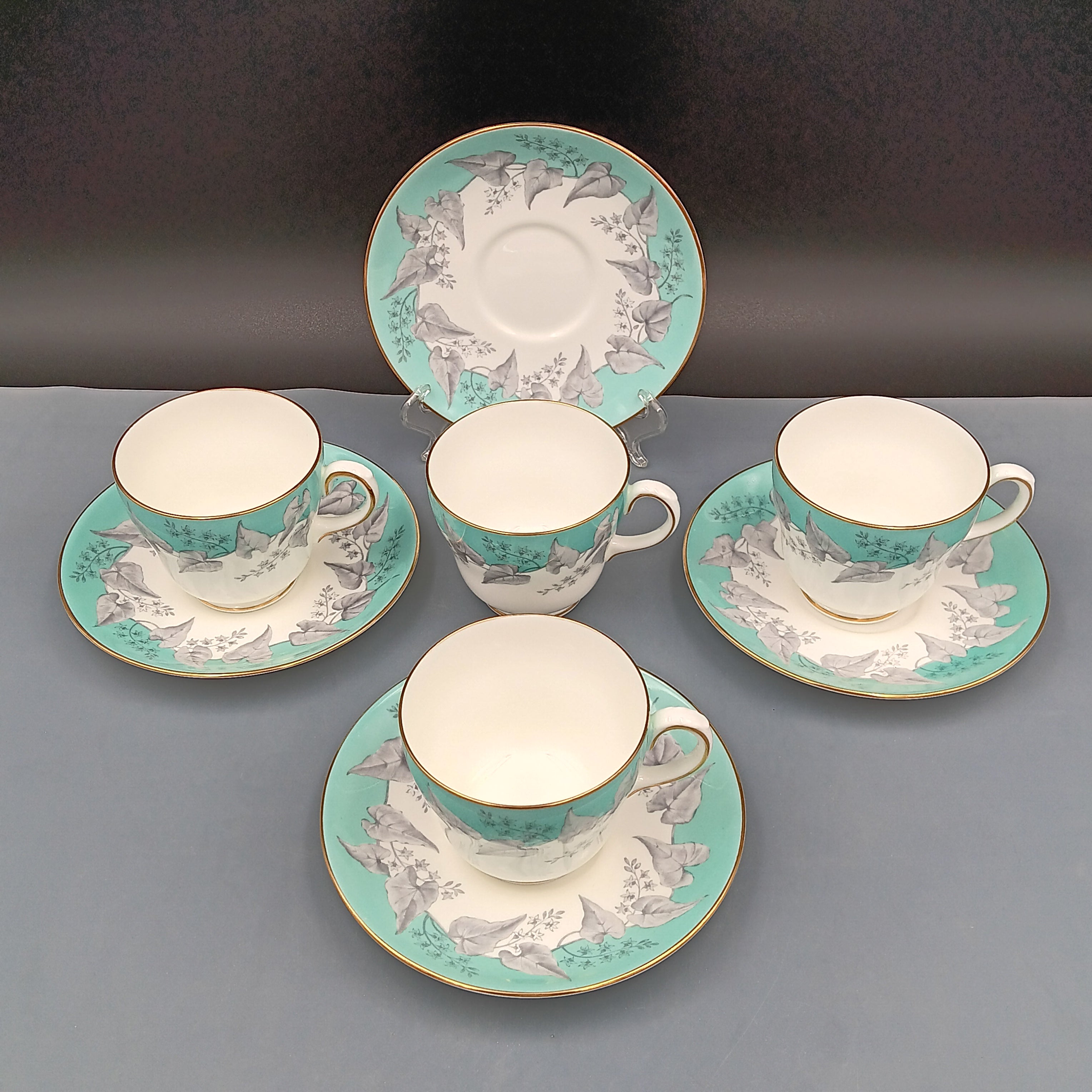 Set of four vintage Wedgwood Buxton Turquoise teacups and saucers with turquoise border, gray floral design, and gold trim