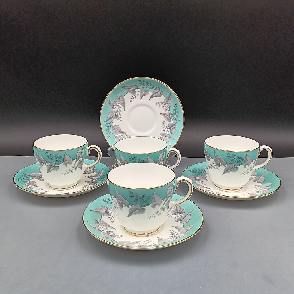 Set of four vintage Wedgwood Buxton Turquoise teacups and saucers with turquoise border, gray floral design, and gold trim
