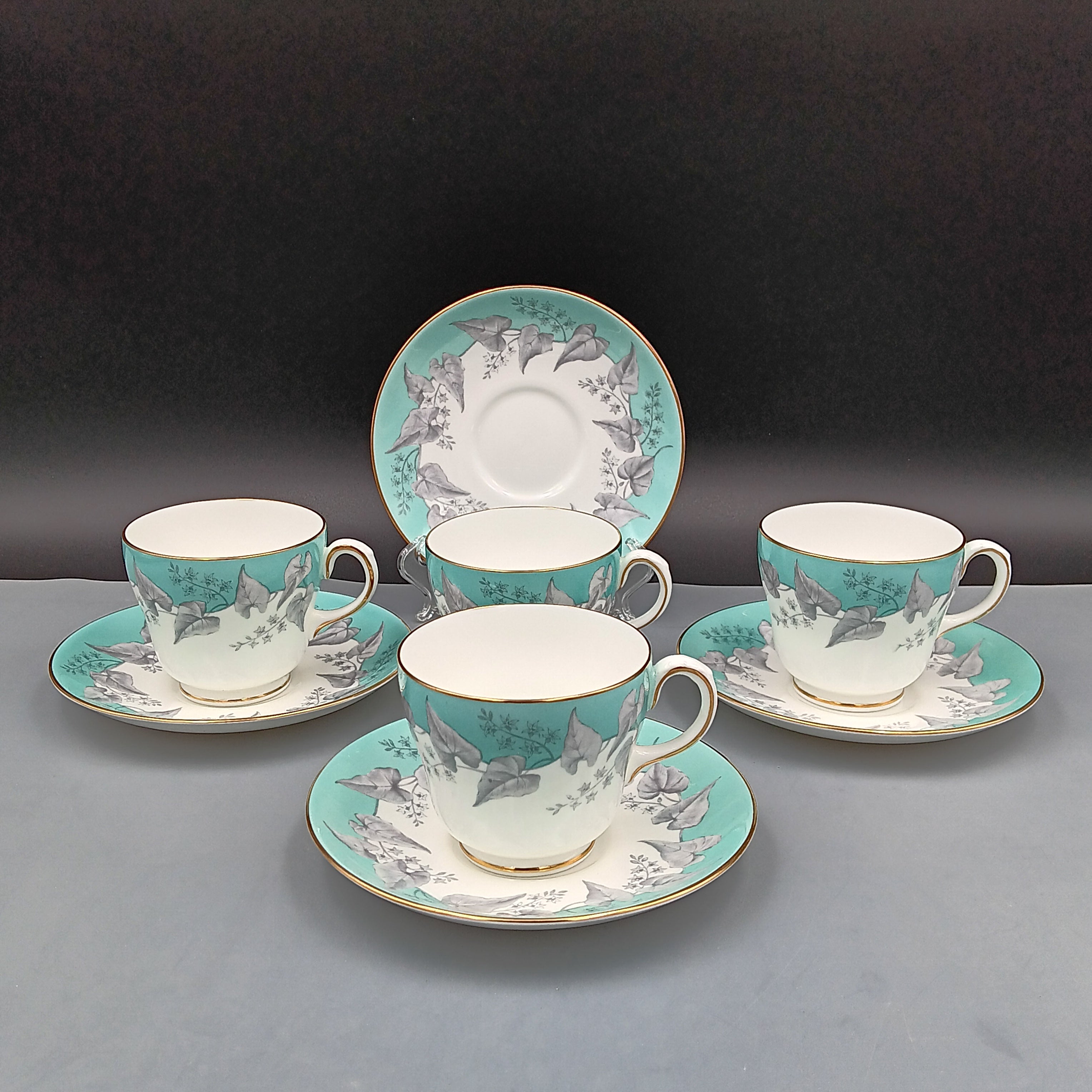 Set of four vintage Wedgwood Buxton Turquoise teacups and saucers with turquoise border, gray floral design, and gold trim