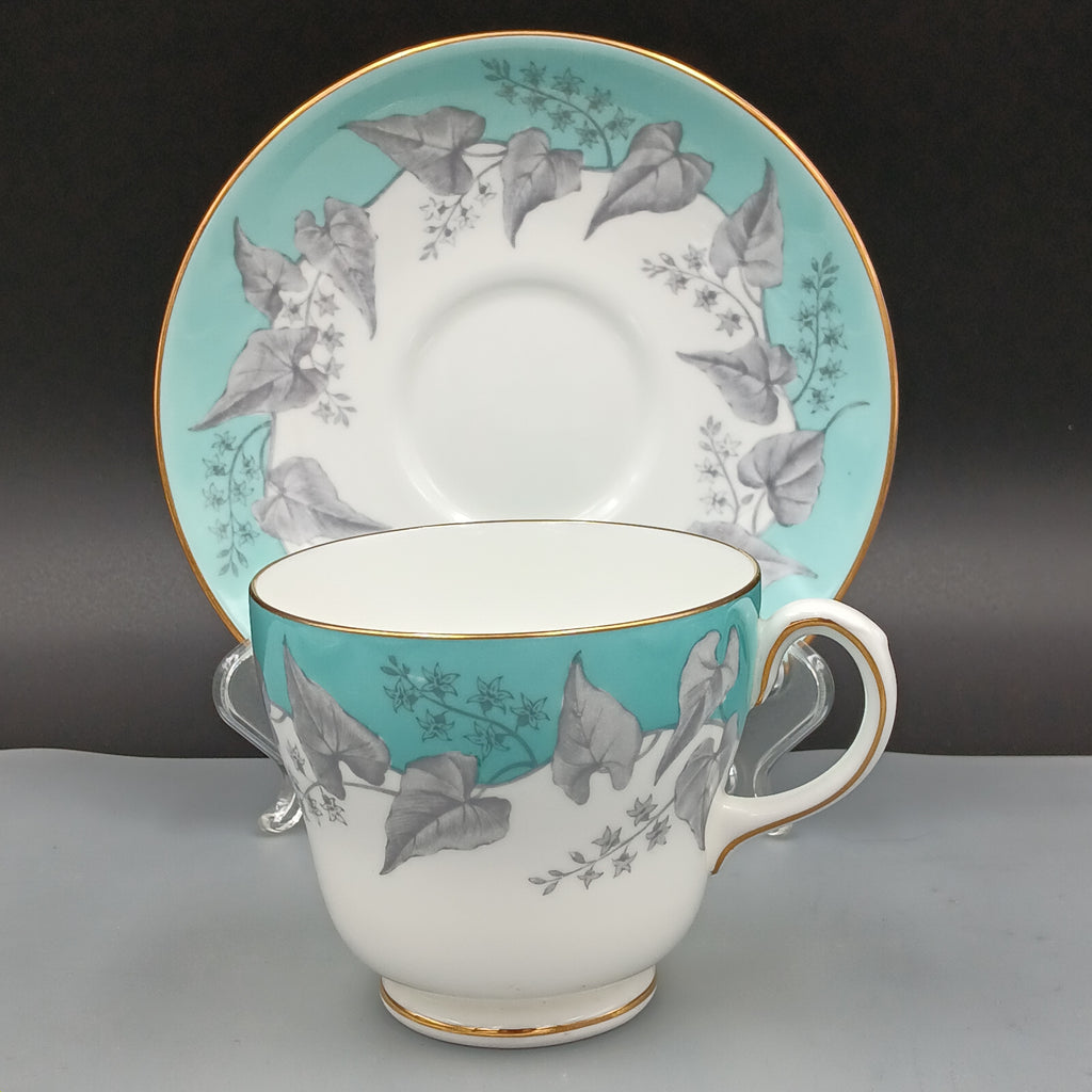 Wedgwood 'Buxton Turquoise teacup and saucer with floral design on a black and gray background.
