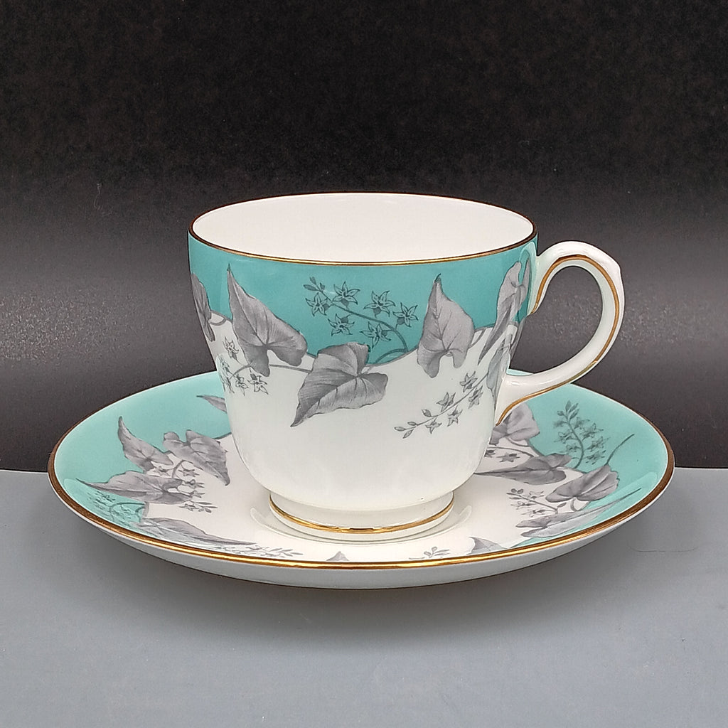 Vintage Wedgwood Buxton Turquoise bone china teacup and saucer set with floral gray leaf pattern, turquoise rim band, and gold trim.