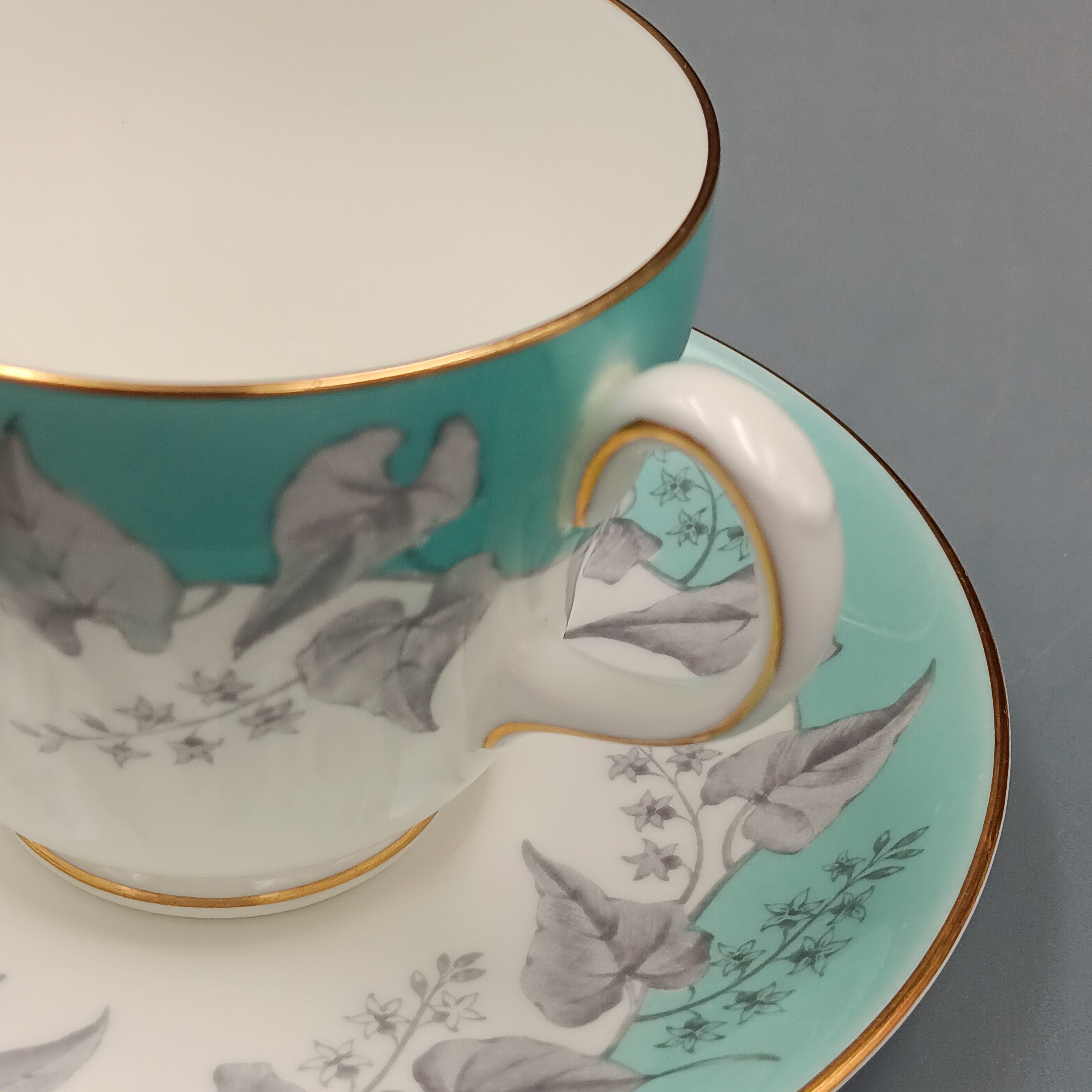 Set of four vintage Wedgwood Buxton Turquoise teacups and saucers with turquoise border, gray floral design, and gold trim