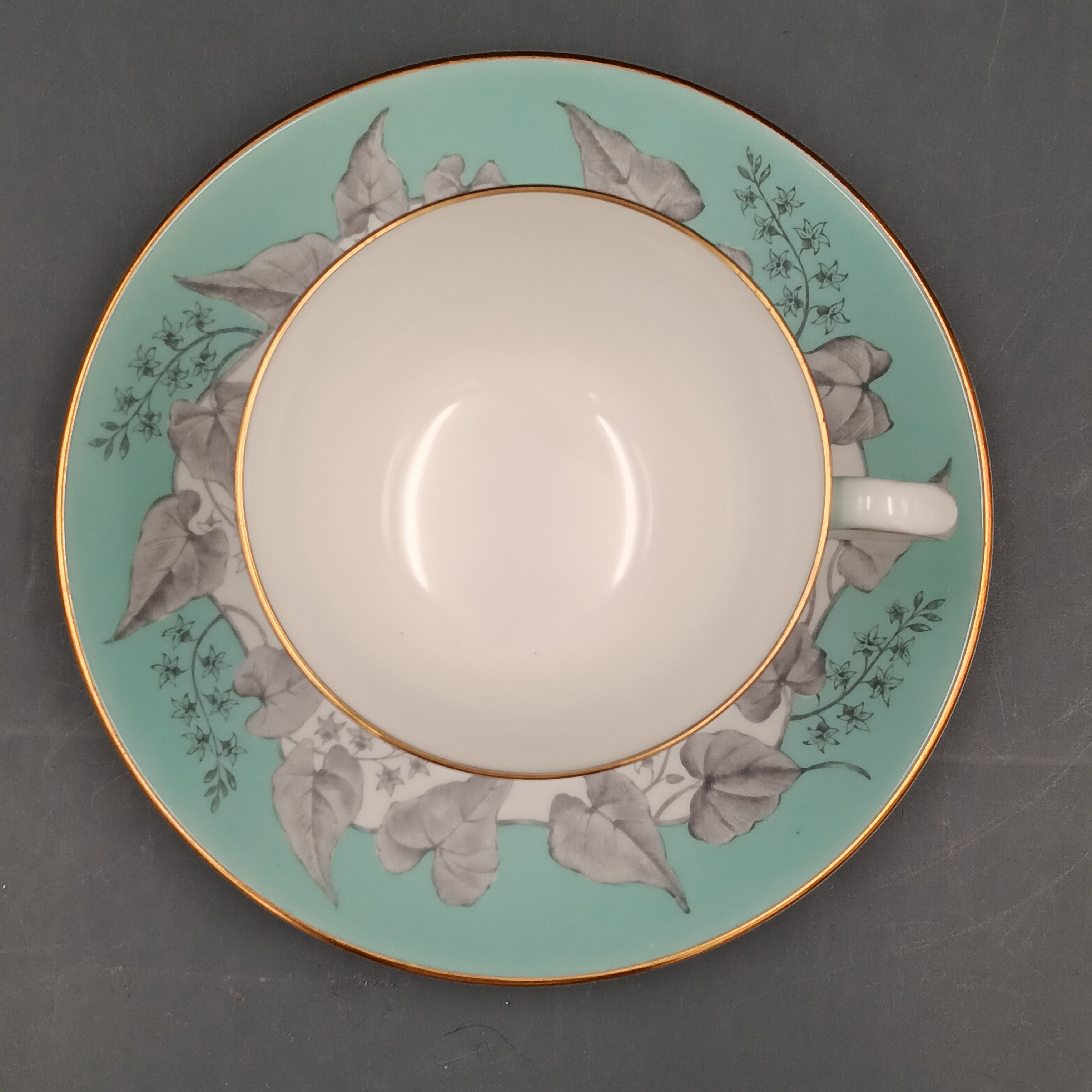 Vintage Wedgwood Buxton Turquoise bone china teacup and saucer set with floral gray leaf pattern, turquoise rim band, and gold trim.