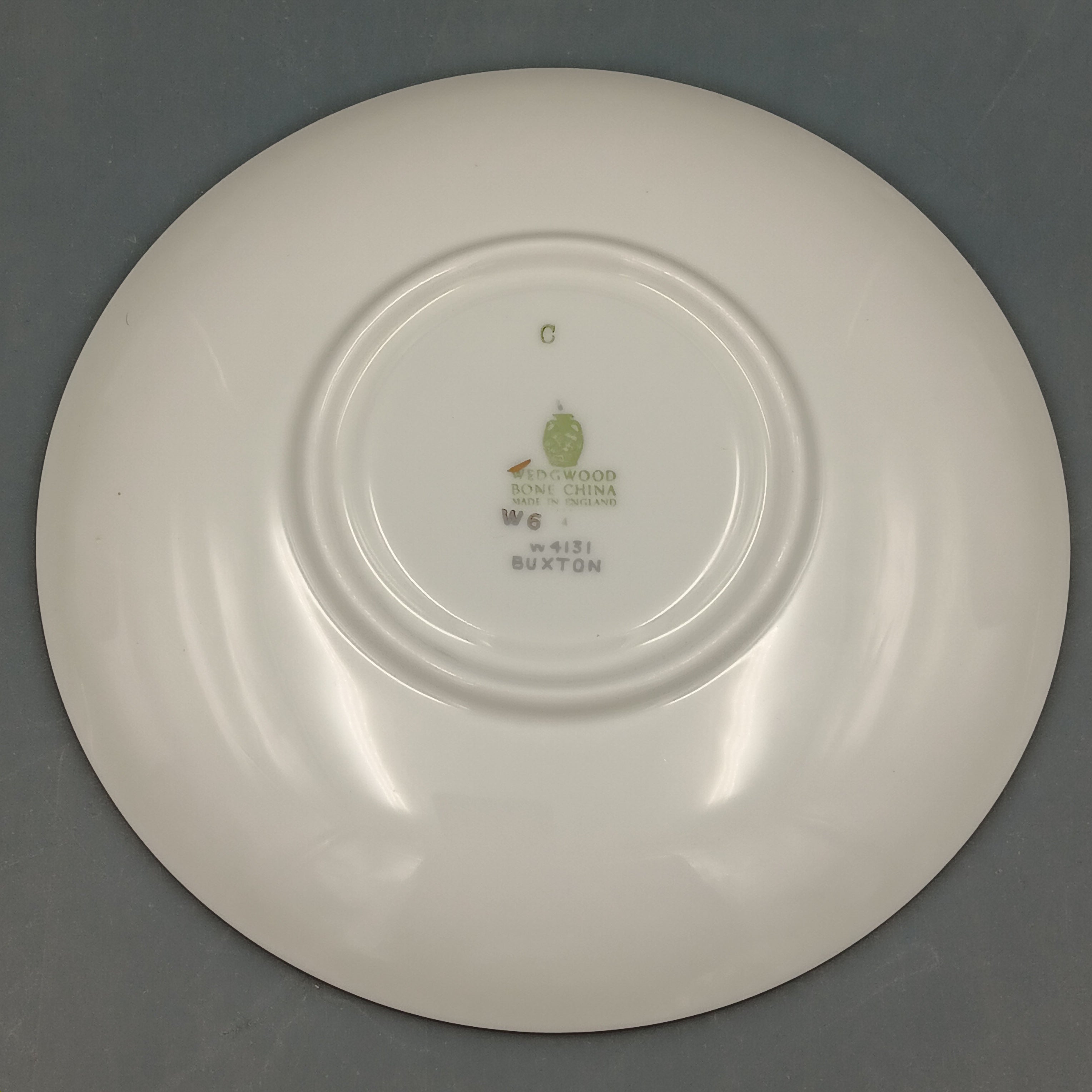 White ceramic plate with a visible brand logo on a gray background