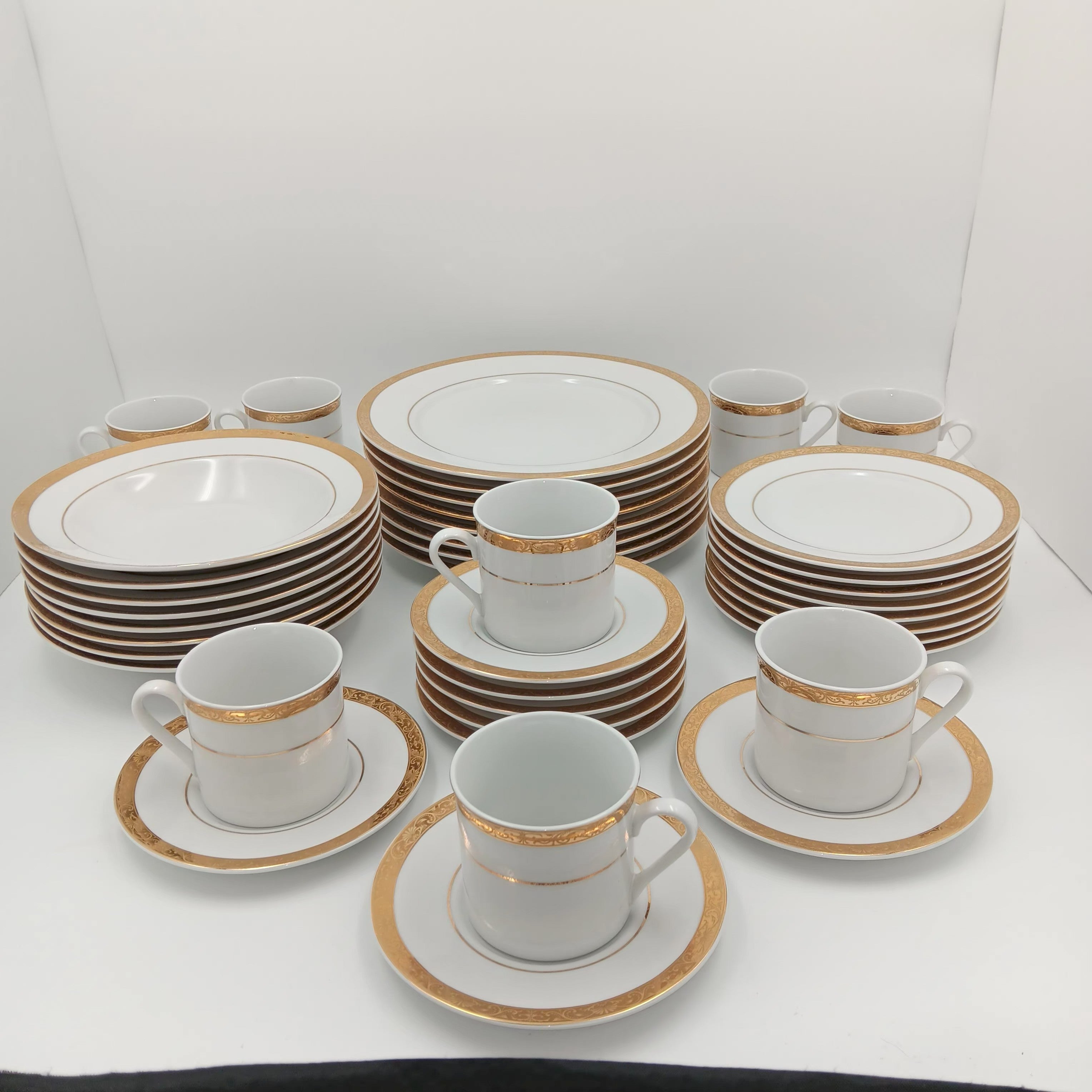 30-piece fine china dinnerware set with white porcelain and gold rim, arranged on white surface